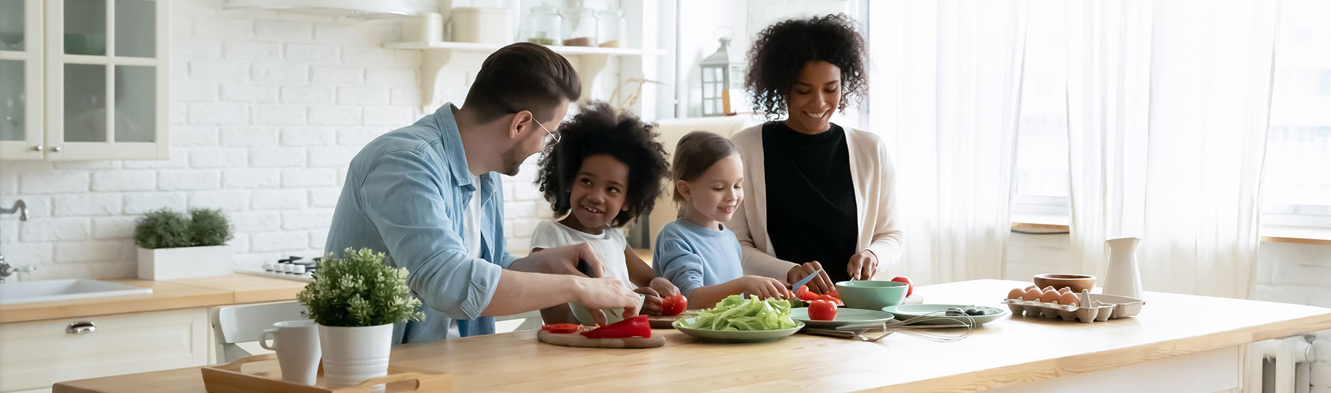 Une famille avec deux enfants sont dans leur cuisine en train de préparer le repas avec des produits Doux