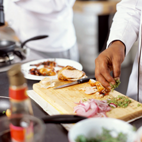 Wooden cutting board with chopped vegetables and slices of Doux chicken