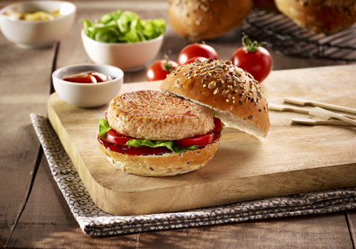 Filete ruso de pollo en una hamburguesa sobre una tabla de cortar de madera