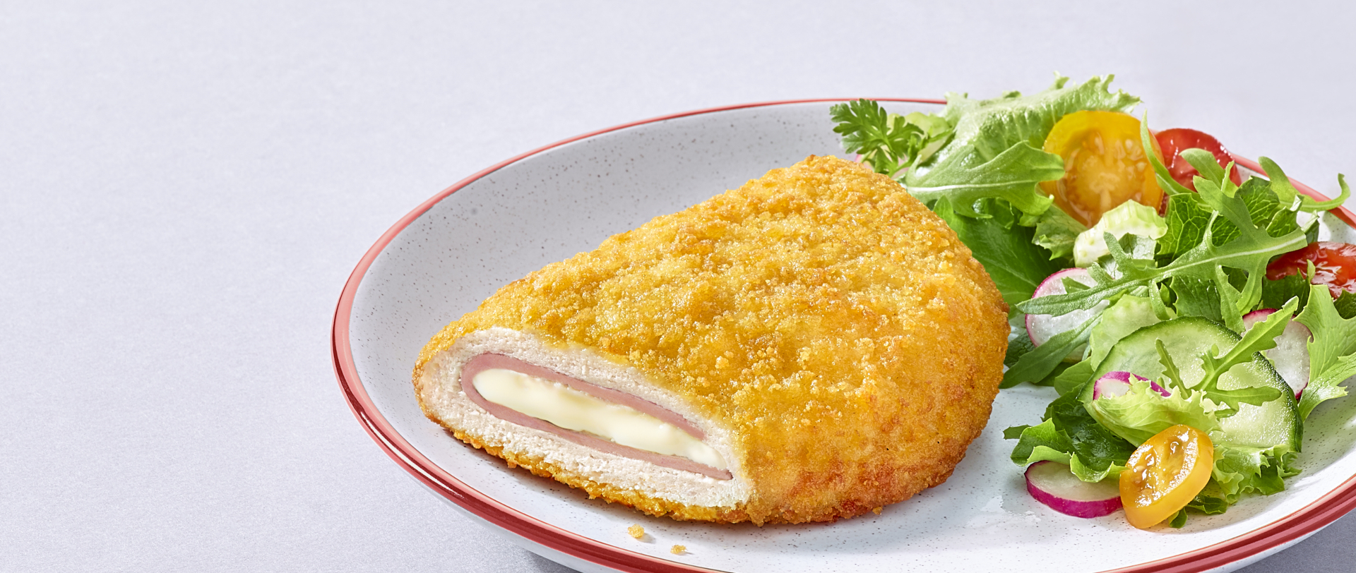 Cordon bleu de dinde Doux sur une assiette blanche avec de la salade et des tomates